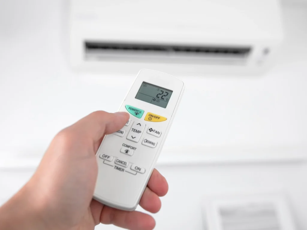 A homeowner adjusting their remote-operated AC.