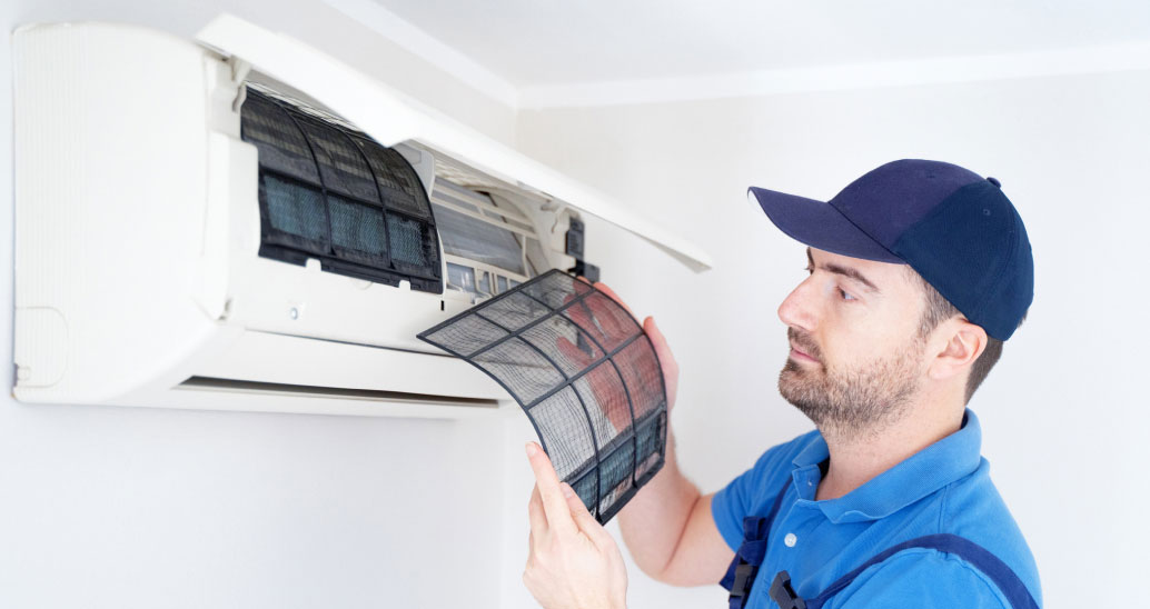 A technician attaching a filter to a newly installed AC system