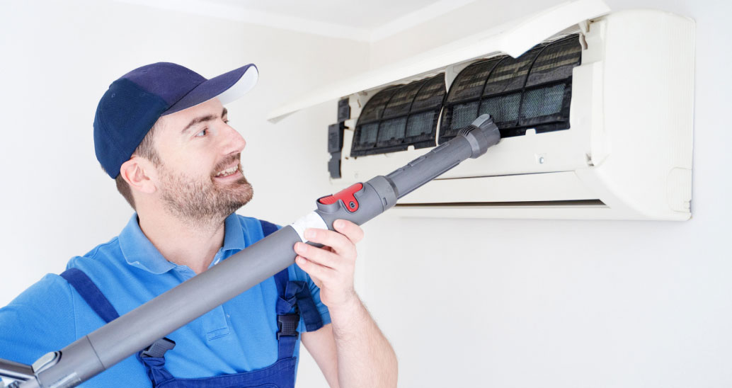 An air conditioning contractor carefully cleans and vacuums the air conditioning